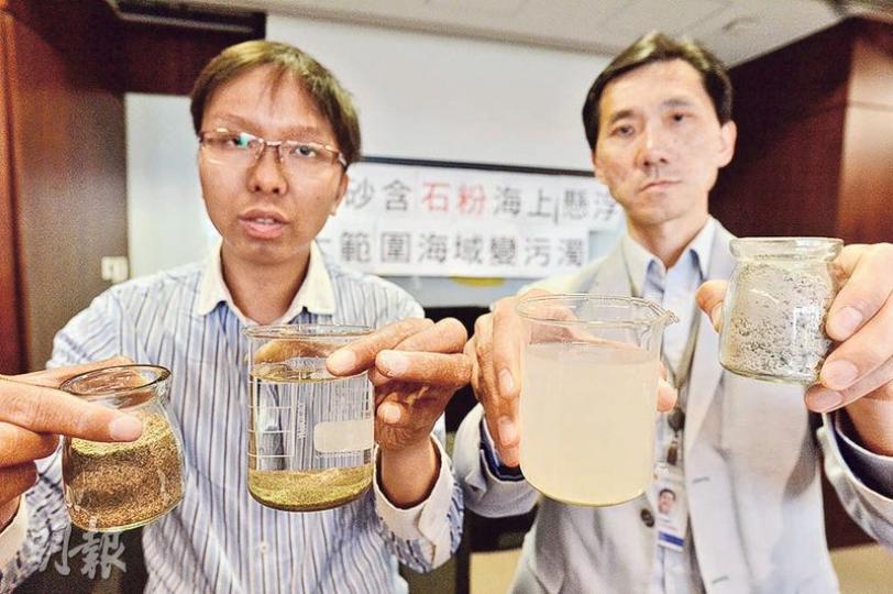 環保觸覺義務總幹事譚凱邦(左)及立法會議員姚松炎(右)批評機管局以機砂代替海砂填海,將加劇海洋污染。譚模擬示範以海砂及機砂的填海狀况,他先將海砂及機砂樣本分別倒入兩杯加上鹽分的清水內,當中海砂倒入左邊水杯後,海砂完全沉降,砂層上方的水較清澈;至於機砂倒入右邊水杯後(姚手持),只有較大粒的砂粒沉下,但砂粒的石粉卻懸浮水中,令水面較渾濁。(馮凱鍵攝) 環保觸覺義務總幹事譚凱邦(左)及立法會議員姚松炎(右)批評機管局以機砂代替海砂填海,將加劇海洋污染。譚模擬示範以海砂及機砂的填海狀况,他先將海砂及機砂樣本分別倒入兩杯加上鹽分的清水內,當中海砂倒入左邊水杯後,海砂完全沉降,砂層上方的水較清澈;至於機砂倒入右邊水杯後(姚手持),只有較大粒的砂粒沉下,但砂粒的石粉卻懸浮水中,令水面較渾濁。(馮凱鍵攝)