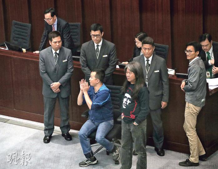 人民力量陳志全(前排左)及社民連梁國雄(前排右)因不滿財委會主席陳健波(後左)限制議員發言時間變相「剪布」,衝上主席台前抗議。擾攘10多分鐘後,陳健波宣布短暫休會。(李紹昌攝) 人民力量陳志全(前排左)及社民連梁國雄(前排右)因不滿財委會主席陳健波(後左)限制議員發言時間變相「剪布」,衝上主席台前抗議。擾攘10多分鐘後,陳健波宣布短暫休會。(李紹昌攝)