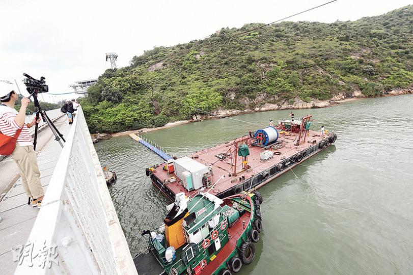 昂坪360纜車近機場島一段鄰近興建中的港珠澳大橋,陸上空間不足,需利用躉船放置牽引纜。(李紹昌攝)更換纜索期間,工程人員需定期爬到纜索上調整纜夾(rope clamp)的鬆緊,以夾穩新纜索。(李紹昌攝) 昂坪360纜車近機場島一段鄰近興建中的港珠澳大橋,陸上空間不足,需利用躉船放置牽引纜。(李紹昌攝)更換纜索期間,工程人員需定期爬到纜索上調整纜夾(rope clamp)的鬆緊,以夾穩新纜索。(李紹昌攝)