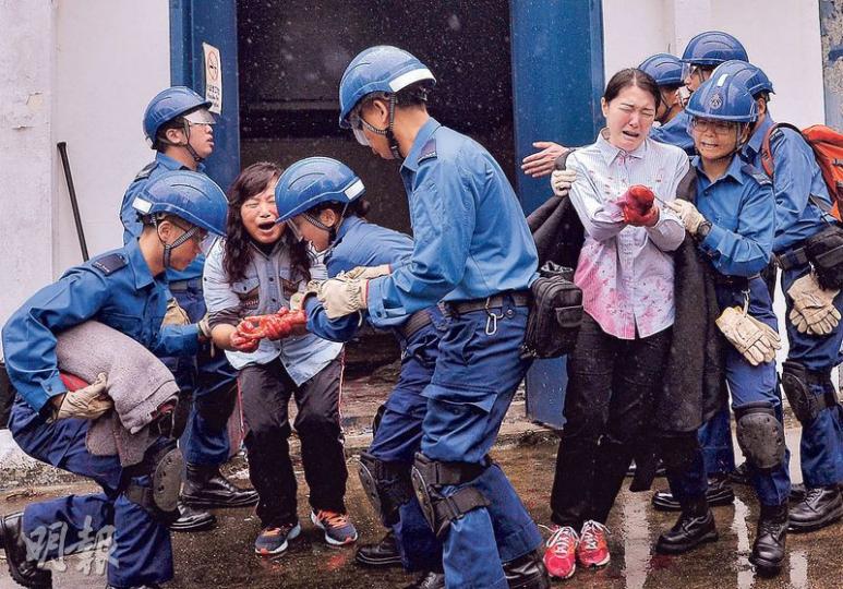 昨日民安隊演習中,人員用鐵筆爆開密室,拯救被困的重傷傷者,當中有女傷者斷肢(右),另一女士(左)手持友人的斷手,民安隊員一邊安撫兩人,一邊為重傷者作基本包紮。(馮凱鍵攝)遇上禽流感爆發,民安隊會配合漁護署撲殺禽鳥,昨日演習亦模擬民安隊穿上高度保護裝備,到雞場「殺雞」。(馮凱鍵攝)民安隊多用不同類型的梯、繩等工具拯救及運送傷者。圖中民安隊人員模擬從樓高一兩層的民居,以「拗梯拯救法」運送平躺在船牀的傷者到地面,原理是船牀以拗梯作承力支撐點,以水平方式運至地面,此法尤其適合運送下肢受傷者,以免運送時因 昨日民安隊演習中,人員用鐵筆爆開密室,拯救被困的重傷傷者,當中有女傷者斷肢(右),另一女士(左)手持友人的斷手,民安隊員一邊安撫兩人,一邊為重傷者作基本包紮。(馮凱鍵攝)遇上禽流感爆發,民安隊會配合漁護署撲殺禽鳥,昨日演習亦模擬民安隊穿上高度保護裝備,到雞場「殺雞」。(馮凱鍵攝)民安隊多用不同類型的梯、繩等工具拯救及運送傷者。圖中民安隊人員模擬從樓高一兩層的民居,以「拗梯拯救法」運送平躺在船牀的傷者到地面,原理是船牀以拗梯作承力支撐點,以水平方式運至地面,此法尤其適合運送下肢受傷者,以免運送時因
