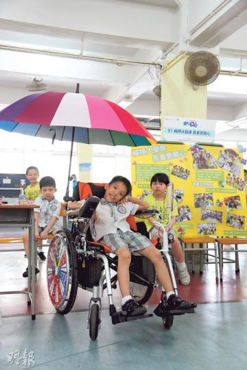浸信會天虹小學學生試坐由11名同學設計的改良輪椅。輪椅因應長者需要,裝上雨傘、電動按摩軟墊和平板電腦,希望長者坐得更開心。(黃志東攝) 浸信會天虹小學學生試坐由11名同學設計的改良輪椅。輪椅因應長者需要,裝上雨傘、電動按摩軟墊和平板電腦,希望長者坐得更開心。(黃志東攝)
