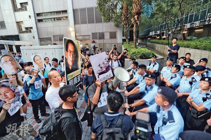 支聯會與民陣昨日先後在灣仔舉行集會,要求釋放劉曉波,其中參加者手持劉曉波圖像抗議,欲遊行至會展,但抵達附近的灣仔稅務大樓時遭警方阻行,雙方對峙,多名警員在場戒備。(李紹昌攝) 支聯會與民陣昨日先後在灣仔舉行集會,要求釋放劉曉波,其中參加者手持劉曉波圖像抗議,欲遊行至會展,但抵達附近的灣仔稅務大樓時遭警方阻行,雙方對峙,多名警員在場戒備。(李紹昌攝)