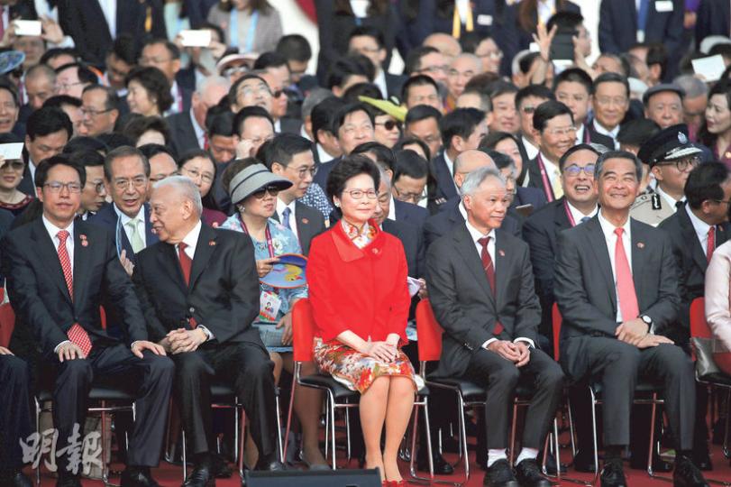 林鄭月娥(前排右三)昨早身穿花旗袍及鮮紅色外套,出席灣仔金紫荊廣場的升旗儀式,其夫林兆波(前排右二)穿上黑色西裝,繫上棗紅色領帶。前排左一為中聯辦主任張曉明,左二為全國政協副主席董建華,右一是剛卸任特首的全國政協副主席梁振英。(曾憲宗攝) 林鄭月娥(前排右三)昨早身穿花旗袍及鮮紅色外套,出席灣仔金紫荊廣場的升旗儀式,其夫林兆波(前排右二)穿上黑色西裝,繫上棗紅色領帶。前排左一為中聯辦主任張曉明,左二為全國政協副主席董建華,右一是剛卸任特首的全國政協副主席梁振英。(曾憲宗攝)