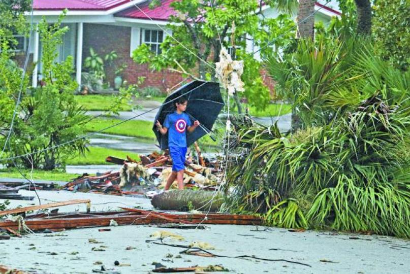 ■棕櫚灣住宅區有屋頂疑遭龍捲風吹散一地，小童小心翼翼走過瓦礫。美聯社