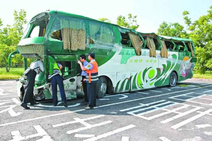 ■肇事長途大巴車頭及左側車身損毀嚴重，警方調查車禍原因。台灣《蘋果日報》■救護人員將傷者抬上救護車送院救治。台灣《蘋果日報》■閉路電視拍到車禍一刻，長途巴出現一道火光。■吳姓司機送院時滿身是血。