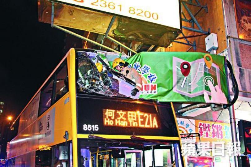 ■肇事巴士車頂陷入大廈簷篷嚴重損毀，消防到上層位置調查。黎家駒攝
