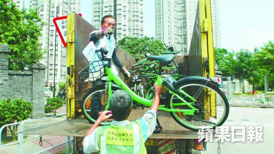■食環署外判工人將違泊單車搬上環保斗貨車運走充公。譚健文攝■地政總署人員在天水圍向79輛違泊單車貼上充公警告。