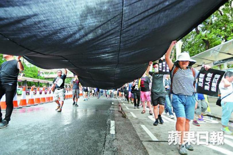 ■遊行人士拉起長長黑布，寓意黑暗來襲。易仰民攝
