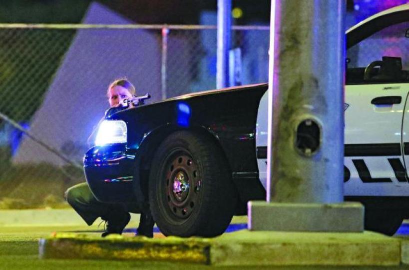 ■一名女警擎槍以警車作掩護戒備。美聯社