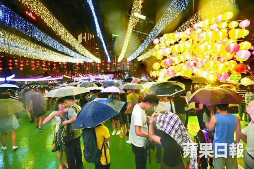 ■昨夜不時下驟雨，維園市民撐傘賞燈無損興致。夏家朗攝■多雲有雨中秋夜，間中仍能看見明月高掛。李家皓攝