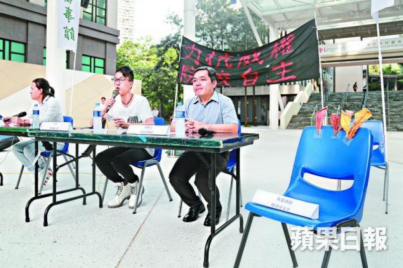 ■論壇一張空凳放有數塊樹葉，諷刺無出席的何君堯疑選舉時自稱執業律師。
