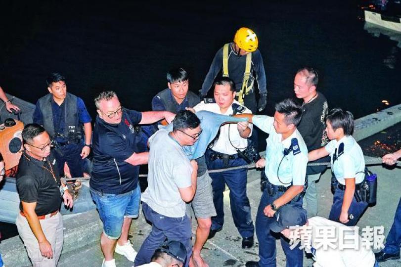■從報案室逃脫跳入屯門河的疑犯被警員押上岸。張家豪攝 ■從報案室逃脫跳入屯門河的疑犯被警員押上岸。張家豪攝