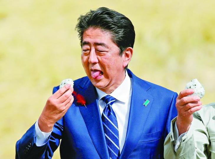 ■安倍吃下福島支持者送上的飯團。 ■安倍吃下福島支持者送上的飯團。