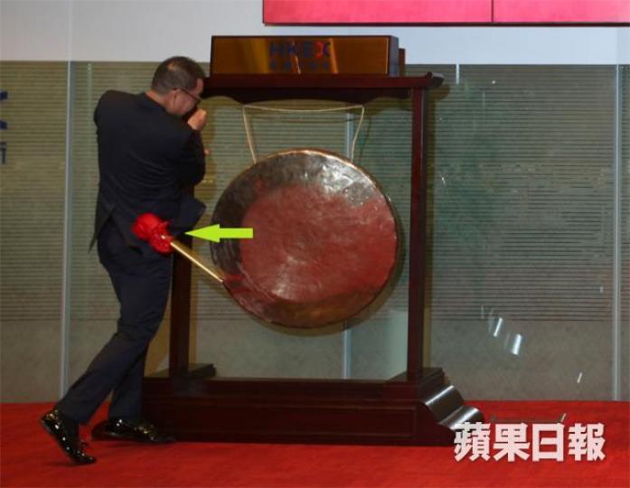 ■黎健新噚日喺上市儀式,敲鑼敲到支棍(箭嘴所示)都飛走埋。李潤芳攝■呢一下敲落去嘅勁度,真係唔講得笑。李潤芳攝 ■黎健新噚日喺上市儀式,敲鑼敲到支棍(箭嘴所示)都飛走埋。李潤芳攝■呢一下敲落去嘅勁度,真係唔講得笑。李潤芳攝