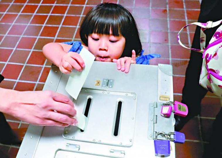 ■小女孩為父親將選票投進票箱。路透社 ■小女孩為父親將選票投進票箱。路透社