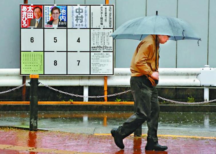 ■投票日適逢颱風吹襲,選民要冒雨去票站投票。路透社 ■投票日適逢颱風吹襲,選民要冒雨去票站投票。路透社