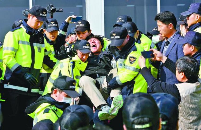 ■南韓昨有大學生在國會前示威反對特朗普到訪,被警員抬走。 ■南韓昨有大學生在國會前示威反對特朗普到訪,被警員抬走。