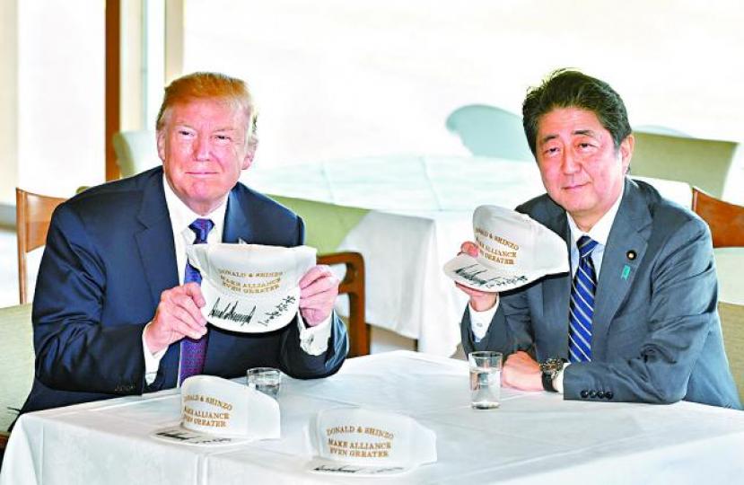 ■特朗普和安倍晉三在印有「讓(美日)聯盟更加偉大」字樣的帽子上簽名。 美聯社 ■特朗普和安倍晉三在印有「讓(美日)聯盟更加偉大」字樣的帽子上簽名。 美聯社