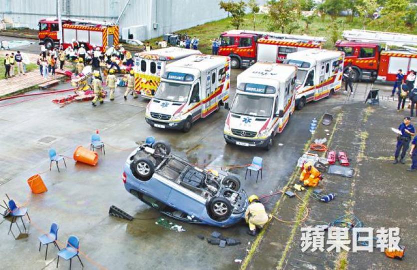 ■有私家車在演習中被撞至四輪朝天。文兆麟攝■多名「傷者」等待救援。 ■有私家車在演習中被撞至四輪朝天。文兆麟攝■多名「傷者」等待救援。