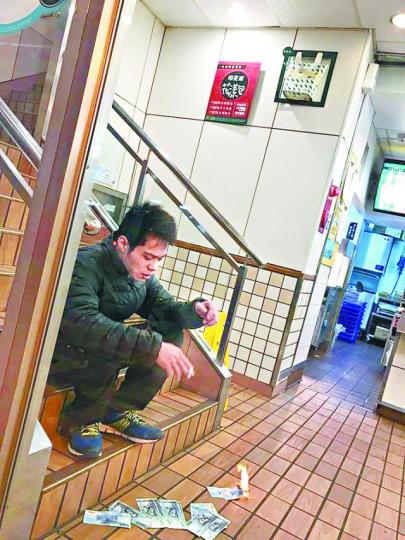 ■姓段男子在快餐店抽煙及燒鈔票。 台灣《蘋果日報》 ■姓段男子在快餐店抽煙及燒鈔票。 台灣《蘋果日報》