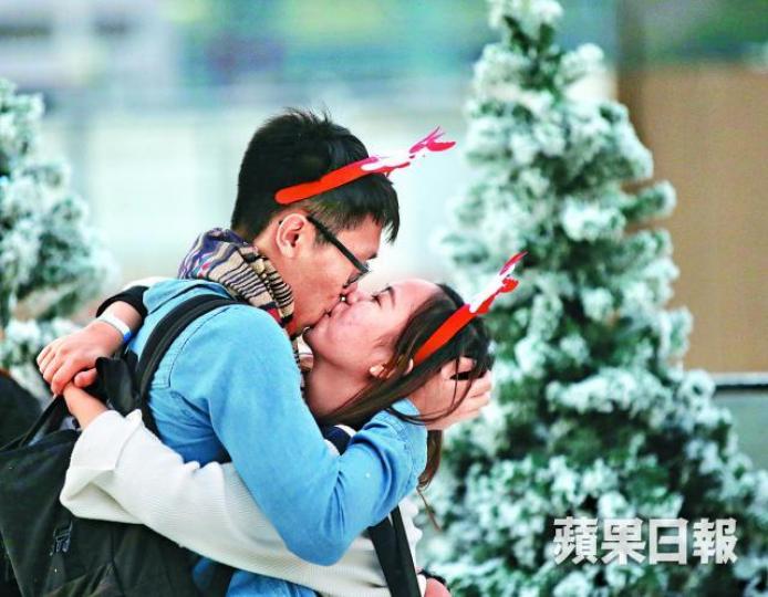 ■聖誕歡樂氣氛下，情侶情不自禁在街上親吻。黎樹雄攝■利東街白雪紛飛，逼滿度佳節市民。王心義攝