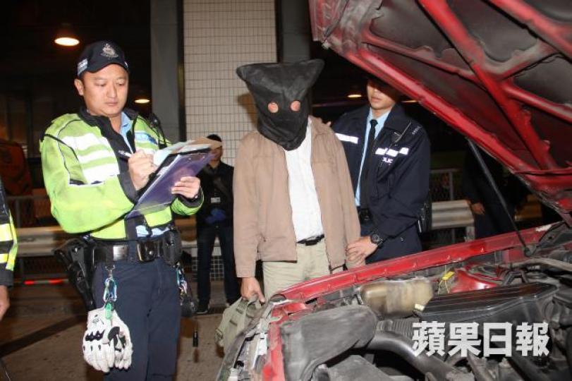 ■警員將涉嫌濫收車資的司機蒙頭帶署。徐雲庭攝 ■警員將涉嫌濫收車資的司機蒙頭帶署。徐雲庭攝