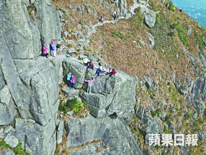 ■飛鵝山自殺崖地勢陡峭,山友為影靚相,冒險越行越出。黃學潤攝■民安隊員游繩到30米下崖底,模擬拯救墮崖傷者。 ■飛鵝山自殺崖地勢陡峭,山友為影靚相,冒險越行越出。黃學潤攝■民安隊員游繩到30米下崖底,模擬拯救墮崖傷者。