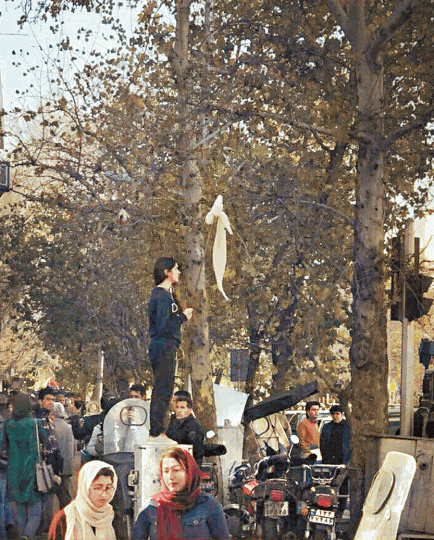 ■伊朗女子脫下白頭巾掛在枝條上揮舞,寓意反抗建制,成為反政府示威浪潮的標記。■馬什哈德最先爆發示威,短片中見鼓譟的民眾疑似向警察擲物。 ■伊朗女子脫下白頭巾掛在枝條上揮舞,寓意反抗建制,成為反政府示威浪潮的標記。■馬什哈德最先爆發示威,短片中見鼓譟的民眾疑似向警察擲物。