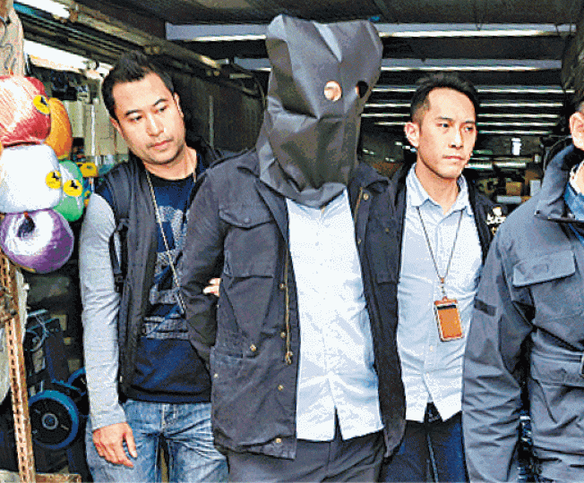 ■其中一名疑犯被警方帶署調查。梁瑞帆攝■警方撿走文件、電腦和充電器(箭嘴示)等證物。 ■其中一名疑犯被警方帶署調查。梁瑞帆攝■警方撿走文件、電腦和充電器(箭嘴示)等證物。