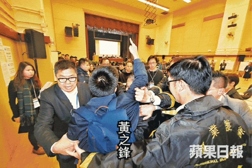 ■黃之鋒衝向鐵馬前抗議,被保安抬離簡介會。■DQ刀手鄧如欣(右)於大會上協助抽籤。何柏佳攝 ■黃之鋒衝向鐵馬前抗議,被保安抬離簡介會。■DQ刀手鄧如欣(右)於大會上協助抽籤。何柏佳攝