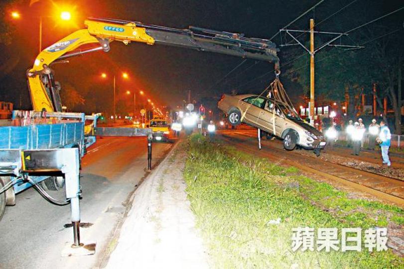 ■港鐵職員用吊臂車將涉事私家車吊離路軌。潘志能攝 ■港鐵職員用吊臂車將涉事私家車吊離路軌。潘志能攝