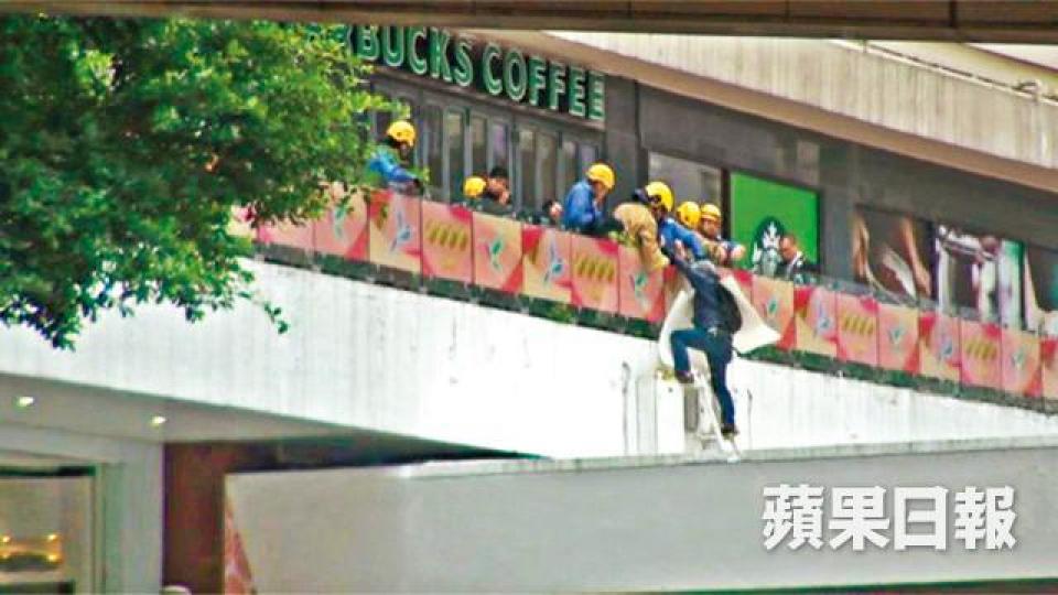■事主昨危站合和簷篷抗議,被勸服後在消防協助下返回安全地方。張培生攝樂景園 ■事主昨危站合和簷篷抗議,被勸服後在消防協助下返回安全地方。張培生攝樂景園