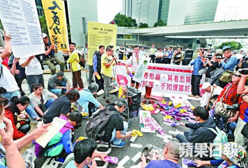 ■遊行人士在添馬街集會,集體打小人表達對預算案的不滿。李家皓攝■市民用拖鞋拍打代表陳茂波及林鄭月娥的道具。 ■遊行人士在添馬街集會,集體打小人表達對預算案的不滿。李家皓攝■市民用拖鞋拍打代表陳茂波及林鄭月娥的道具。