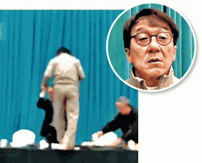■成龍(圓圖)受訪後,在他人撐扶下攀上會議桌,返回座位。有線畫面 ■成龍(圓圖)受訪後,在他人撐扶下攀上會議桌,返回座位。有線畫面