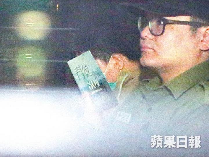 ■被告劉璋輝乘囚車時以封面印有「門徒」的書掩面。陳善南攝