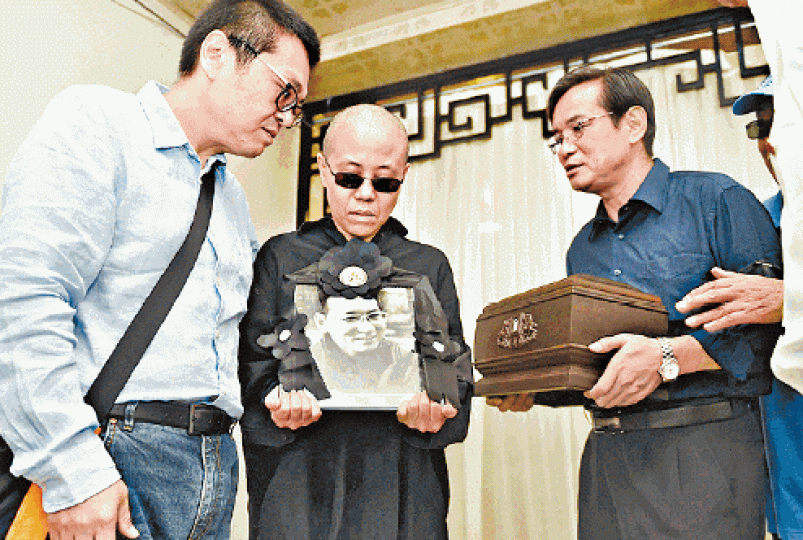 ■劉曉波火化當日,妻子劉霞手捧其遺照,弟弟劉曉暄則手捧其骨灰。 ■劉曉波火化當日,妻子劉霞手捧其遺照,弟弟劉曉暄則手捧其骨灰。