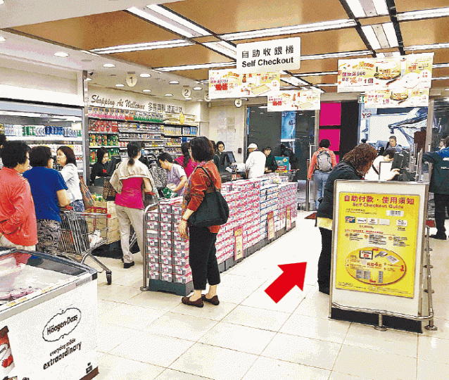 ■大部份顧客仍選擇排隊結賬,自助收銀機(箭嘴示)較少人使用。譚德潤攝■惠康的自助收銀機只接受八達通等電子支付工具。 ■大部份顧客仍選擇排隊結賬,自助收銀機(箭嘴示)較少人使用。譚德潤攝■惠康的自助收銀機只接受八達通等電子支付工具。