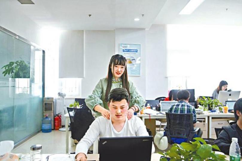 ■在北京中望金服任職「程序員鼓勵師」的申悅，擁有土木工程學位，圖為她正為一名同事按摩。