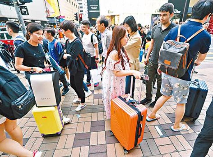 ■內地五一假期展開,尖沙嘴昨有不少拖篋旅客穿插人群。謝榮耀攝 ■內地五一假期展開,尖沙嘴昨有不少拖篋旅客穿插人群。謝榮耀攝