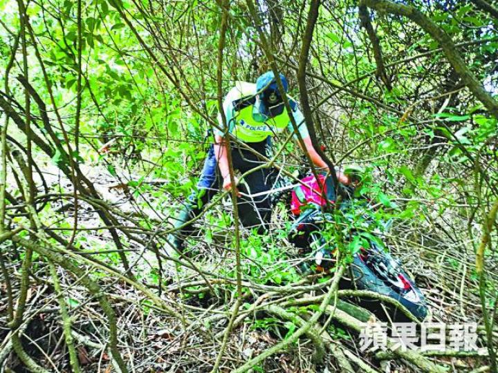 ■警員到場調查,並撿走鏟落山坡的電單車。文兆麟攝 ■警員到場調查,並撿走鏟落山坡的電單車。文兆麟攝
