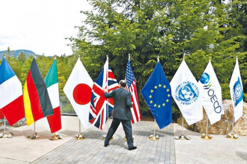 ■G7財長會議風雨飄搖,會場外亦刮大風,有代表抓着快要被吹脫的旗幟。 ■G7財長會議風雨飄搖,會場外亦刮大風,有代表抓着快要被吹脫的旗幟。
