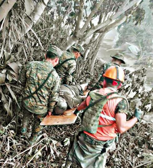 ■軍警在山區抬走一名罹難者。美聯社 ■軍警在山區抬走一名罹難者。美聯社