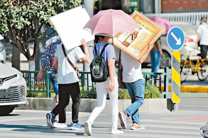 ■西安市民出行時開傘遮擋陽光。中新社 ■西安市民出行時開傘遮擋陽光。中新社