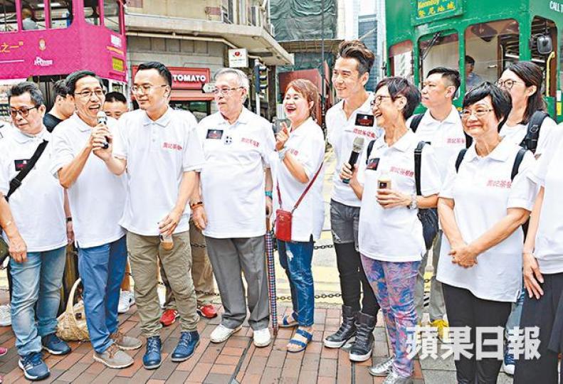 ■(左三起)監製「拉表叔」馮志豐、「周老闆」金剛、林建明及唐文龍等在鬧市宣傳。■廣播劇《十八樓C座》不經不覺已經五十周年,一班演員坐電車出巡。■唐文龍派飲品,吸引大批市民圍觀。 ■(左三起)監製「拉表叔」馮志豐、「周老闆」金剛、林建明及唐文龍等在鬧市宣傳。■廣播劇《十八樓C座》不經不覺已經五十周年,一班演員坐電車出巡。■唐文龍派飲品,吸引大批市民圍觀。