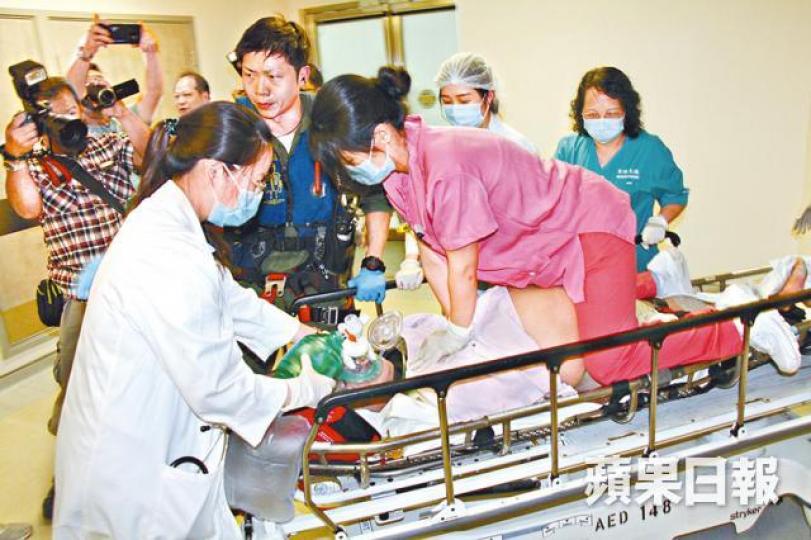 ■事主由擔架床送院,醫護人員為他施心外壓。胡恩宏攝 ■事主由擔架床送院,醫護人員為他施心外壓。胡恩宏攝