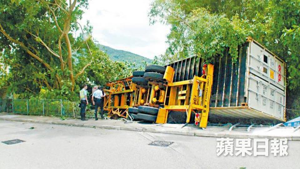 ■涉事貨櫃車撞毀鐵欄及燈柱後,鏟上行人路翻側。 ■涉事貨櫃車撞毀鐵欄及燈柱後,鏟上行人路翻側。