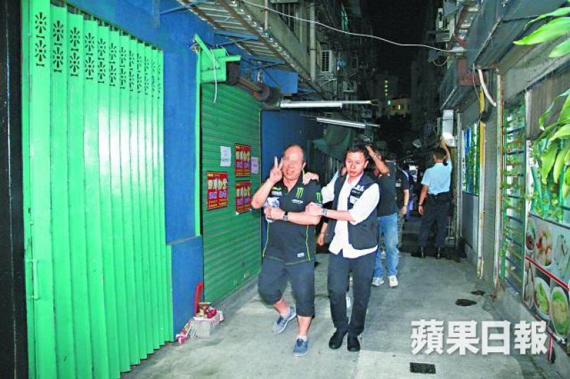■元朗一間無牌酒吧被警方搗破,有男酒客被捕時舉起V字手勢。唐家輝攝 ■元朗一間無牌酒吧被警方搗破,有男酒客被捕時舉起V字手勢。唐家輝攝