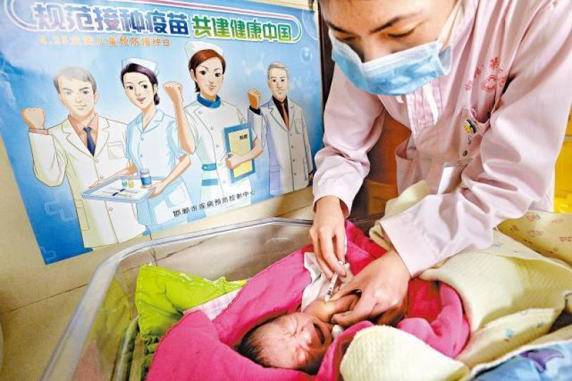 ■內地醫院護士為嬰兒接種疫苗,旁邊海報寫着「規範接種疫苗共建健康中國」。美聯社 ■內地醫院護士為嬰兒接種疫苗,旁邊海報寫着「規範接種疫苗共建健康中國」。美聯社