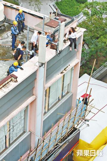 ■女事主危坐天台邊,消防員於地面張開氣墊戒備。 ■女事主危坐天台邊,消防員於地面張開氣墊戒備。