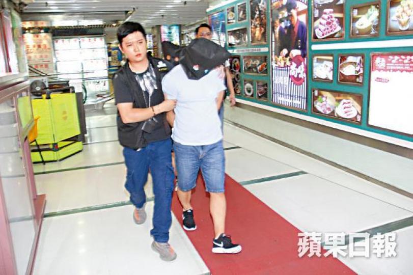 ■涉案兩名內地男子被探員蒙頭押走。溫文學攝 ■涉案兩名內地男子被探員蒙頭押走。溫文學攝